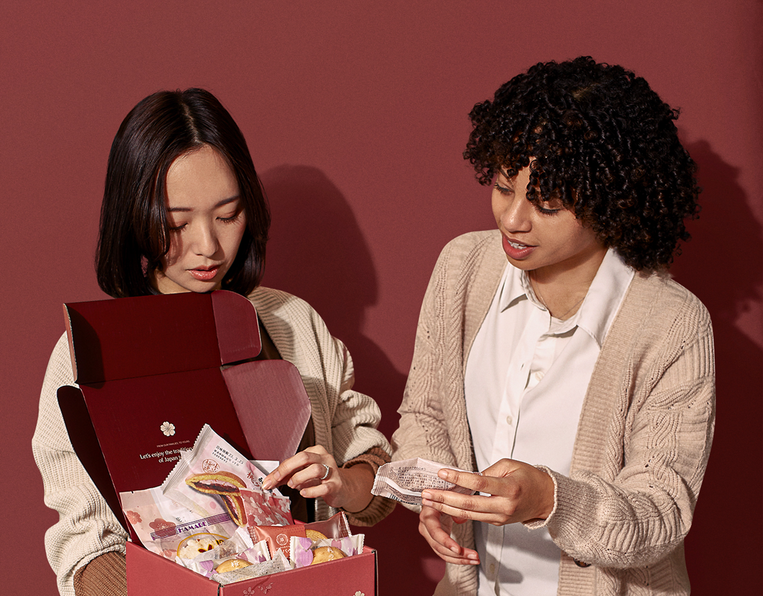 Ayumi Chikamoto and friend look at the authentic Japanese snacks and tea in Sakuraco's subscription snack box.